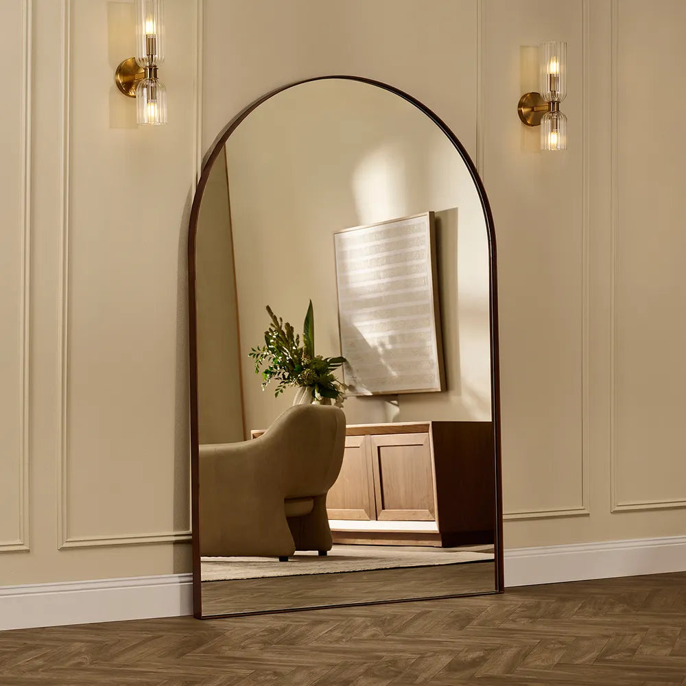 Large arched mirror on a wall with a reflection of a room.